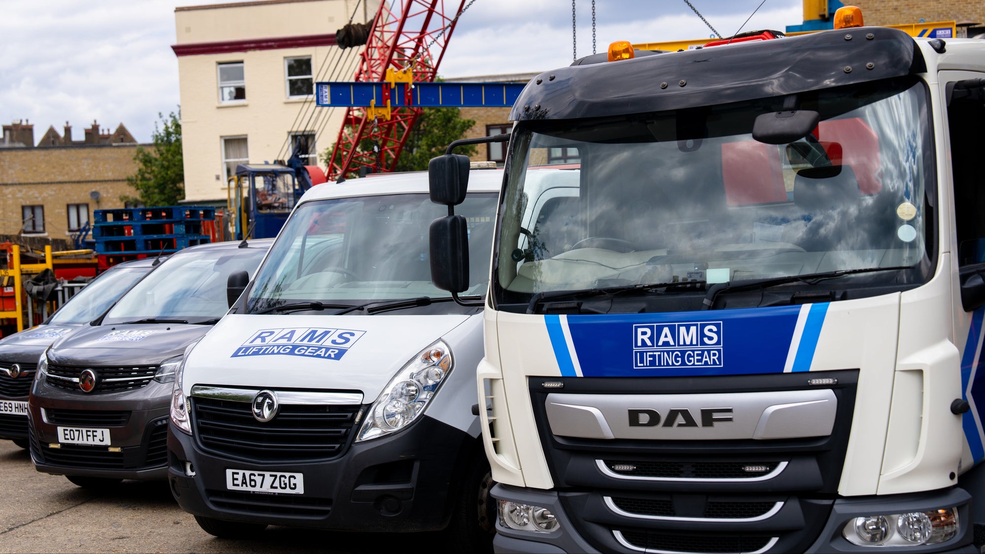 Two vans with 'RAMS' branding parked in a lot with construction equipment in the background.